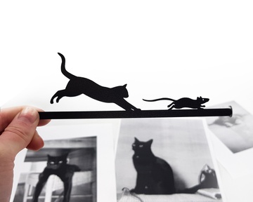Black Metal Bookmark Cat Is Chasing the Mouse. The cat and the mouse are running along the stick which sits between the pages of the book. The little door of the mouse hole is seen on the side of the book even when the book is closed.