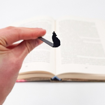 Black metal bookmark Howling Wolf. A flat metal stick stays between the pages of the book, The silhouette of the wolf is on the side of the book. It is visible even when the book is closed. Not mass produced.
