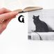 Black metal bookmark - Cat on the Moon. A long, flat metal stick stays between the pages of the book. The cat sitting on the half-moon is on the side of the book. It is visible even when the book is closed, made by us in Ukraine.